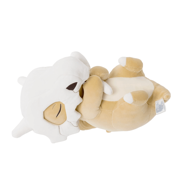 Coussin Osselait en peluche beige et blanc, avec un crâne blanc sur le visage, allongé et tenant un os.