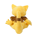 peluche Abra jaune en tissu doux, vue de dos, avec une longue queue et un col brun autour du cou