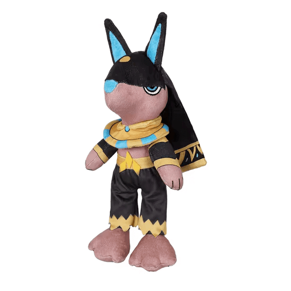 Peluche Anubis aux oreilles noires et bleues, avec foulard doré et bleu, pantalon noir et cape ornée de motifs égyptiens.