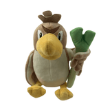 Peluche Canarticho Pokémon aux plumes brunes et beiges, au grand bec jaune, tenant une tige verte en forme de poireau.