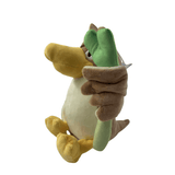 Peluche Canarticho au bec et aux pattes jaunes, ventre crème, tenant une grande tige verte dans son aile brune.