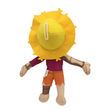 Peluche peluche Hector aux membres couleur os, pantalon orange et haut bordeaux, avec une grande tête jaune en forme de soleil