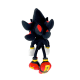 Peluche Shadow en tissu noir, avec des détails rouges, des gants blancs et de grandes chaussures rouges et jaunes.