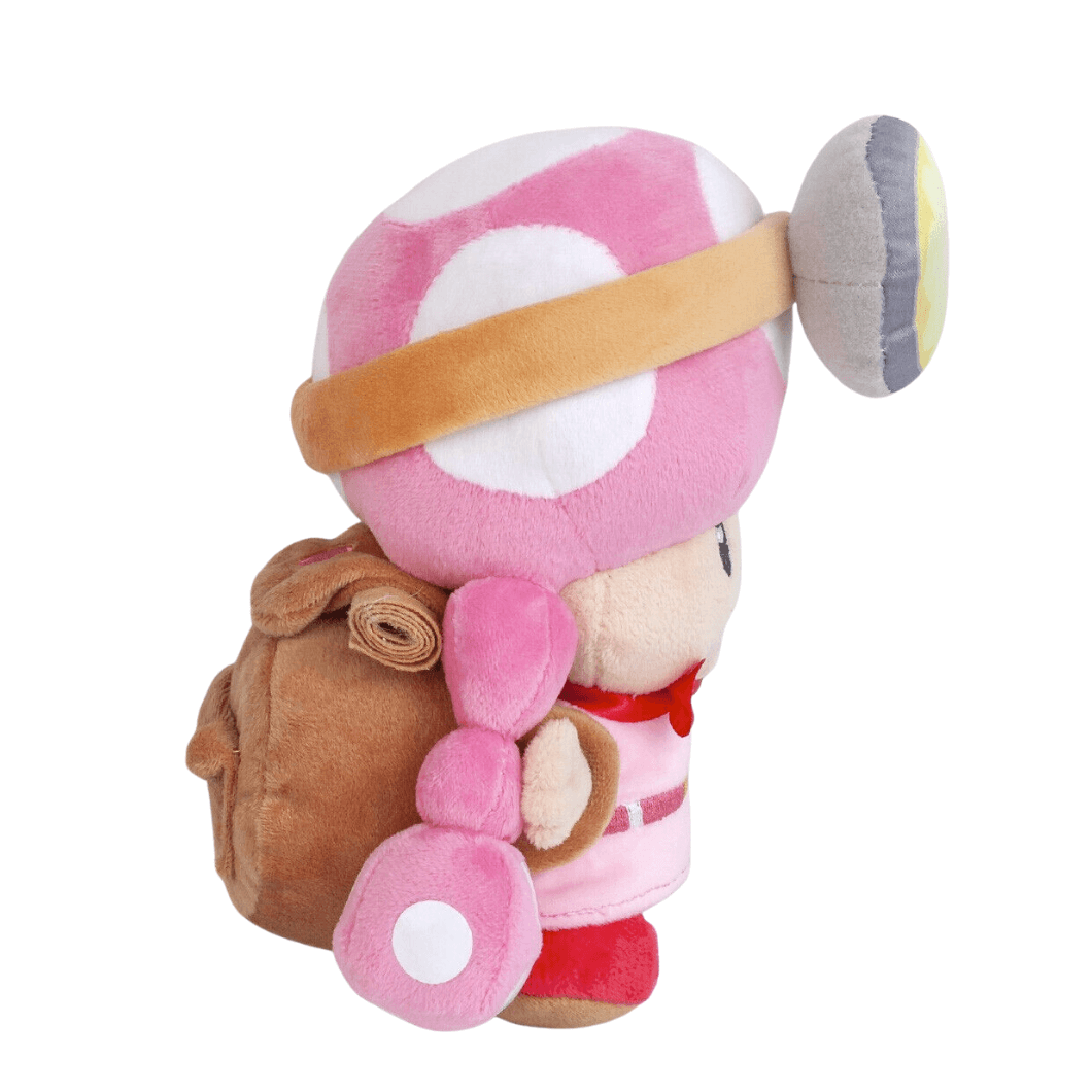 Peluche Toadette rose et blanche en tissu doux, avec chignon à pois, bandeau beige et sac à dos brun.